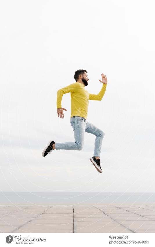 Unbeschwerter junger Mann springt auf Fußweg gegen weiße Wand Farbaufnahme Farbe Farbfoto Farbphoto Spanien Freizeitbeschäftigung Muße Zeit Zeit haben