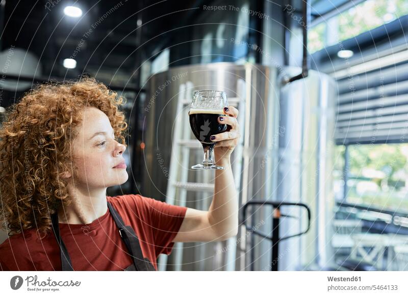 Frau, die in einer handwerklichen Brauerei arbeitet und die Qualität eines Bieres prüft Job Berufe Berufstätigkeit Beschäftigung Jobs Gläser Trinkglas