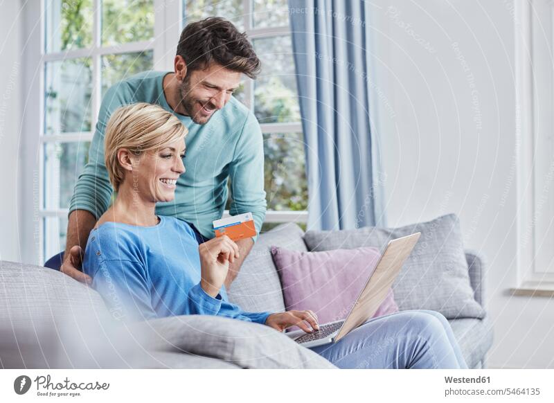 Glückliches Paar beim Online-Shopping zu Hause einkaufen shoppen Einkauf Zuhause daheim Pärchen Paare Partnerschaft glücklich glücklich sein glücklichsein