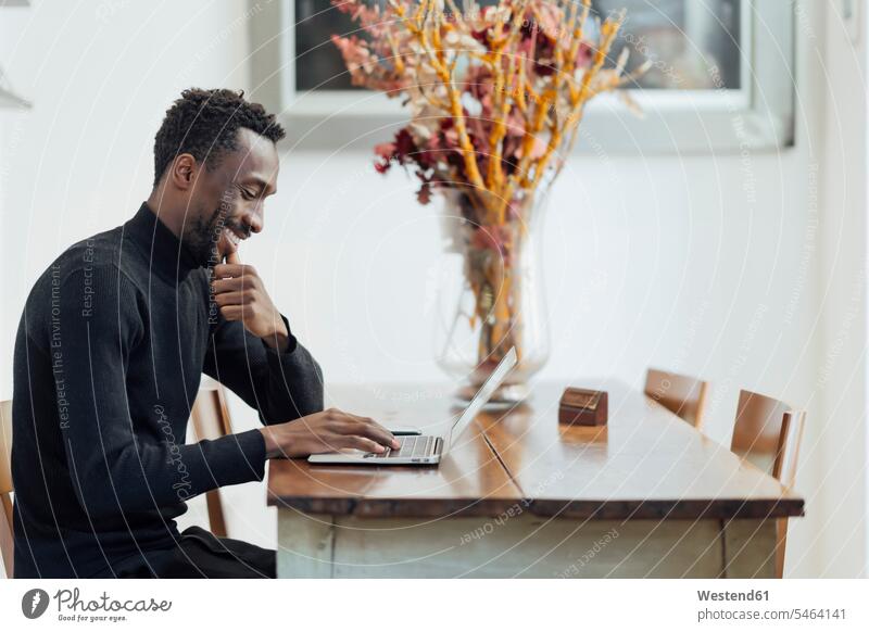 Junger Unternehmer arbeitet am Laptop, während er im Café sitzt Farbaufnahme Farbe Farbfoto Farbphoto Außenaufnahme außen draußen im Freien Tag