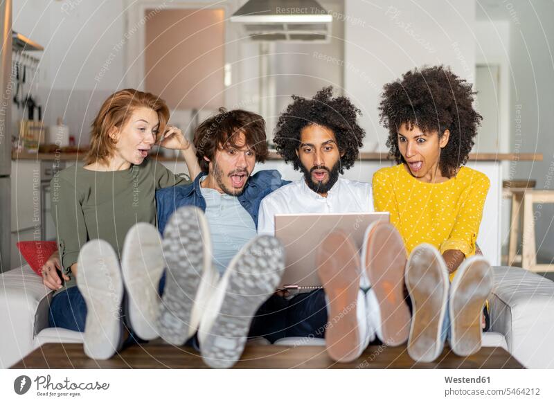 Freunde sitzen auf der Couch, beobachten Laptop Spanien Multikulturelle Gruppe multikulturell Wohnen Schuhsohle Sohle Schuhsohlen Sohlen differenzierter Fokus