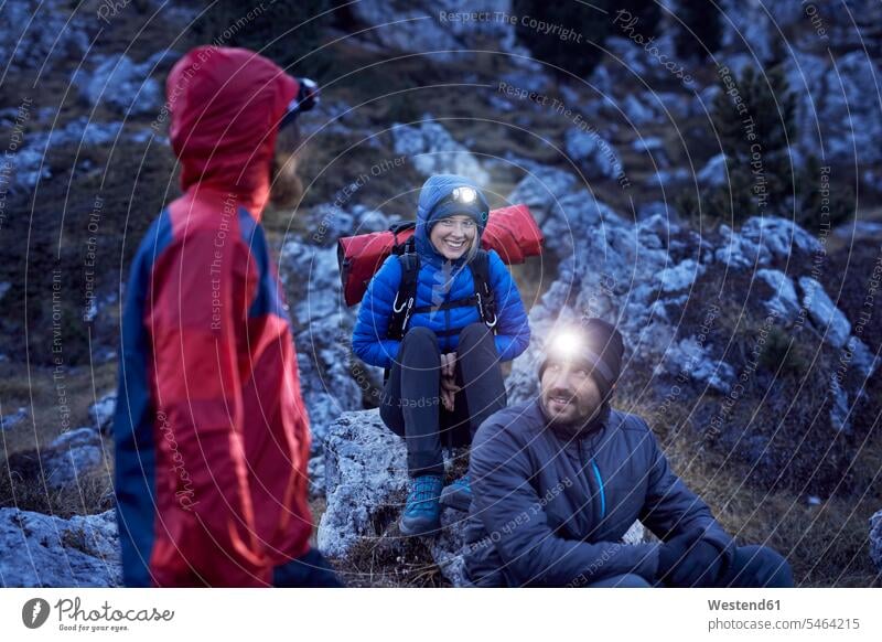 Lächelnde Bergsteiger mit Stirnlampen in den Bergen in der Abenddämmerung Kopfleuchte Kopflampe Freunde stimmungsvoll Stimmung Dämmerung Abendstimmung