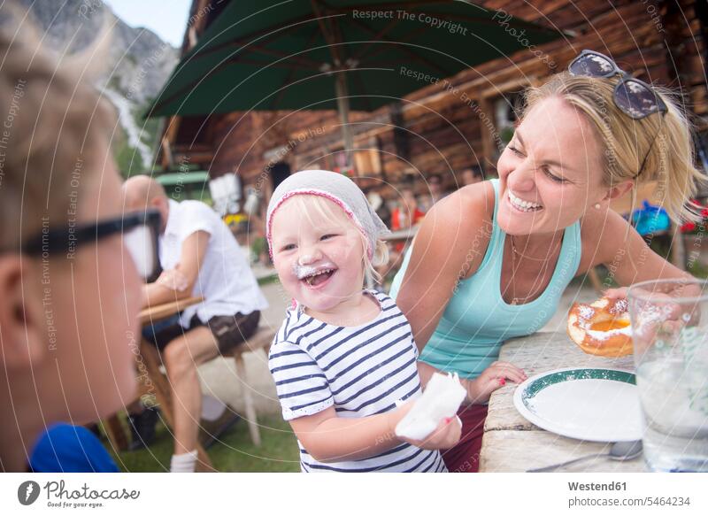 Fröhliches kleines Mädchen isst Kuchen mit der Familie in der Alphütte Familien wandern Wanderung weiblich essen essend Pause ländlich auf dem Land