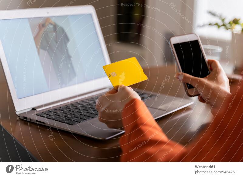 Ausgeschnittenes Bild einer Geschäftsfrau mit Kreditkarte, die ein Smartphone benutzt, während sie zu Hause online einkauft Farbaufnahme Farbe Farbfoto