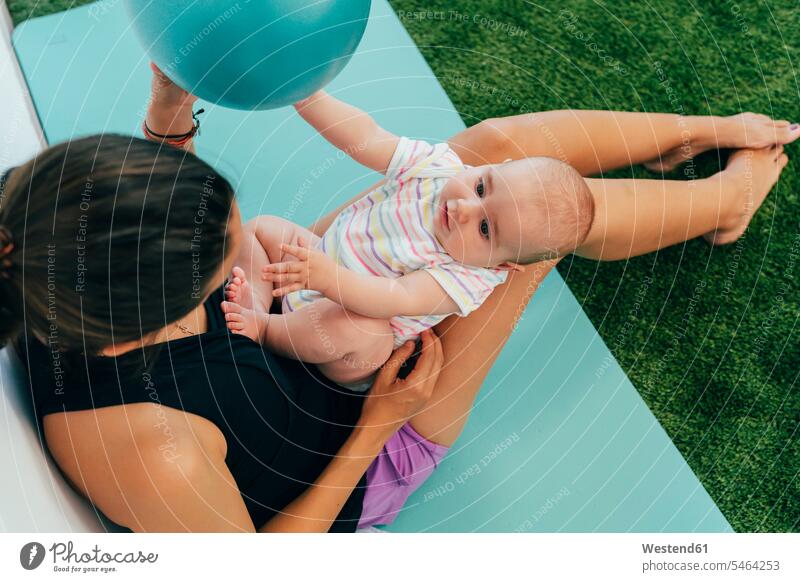 Junge Mutter und Baby üben auf der Yogamatte, spielen mit einem Ball Bälle sitzend sitzt Glück glücklich sein glücklichsein innig nah zufrieden fit gesund