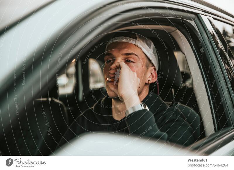 Junger Mann raucht Zigarette beim Autofahren Außenaufnahme außen draußen im Freien Tag Tageslichtaufnahme Tageslichtaufnahmen Tagesaufnahme am Tag