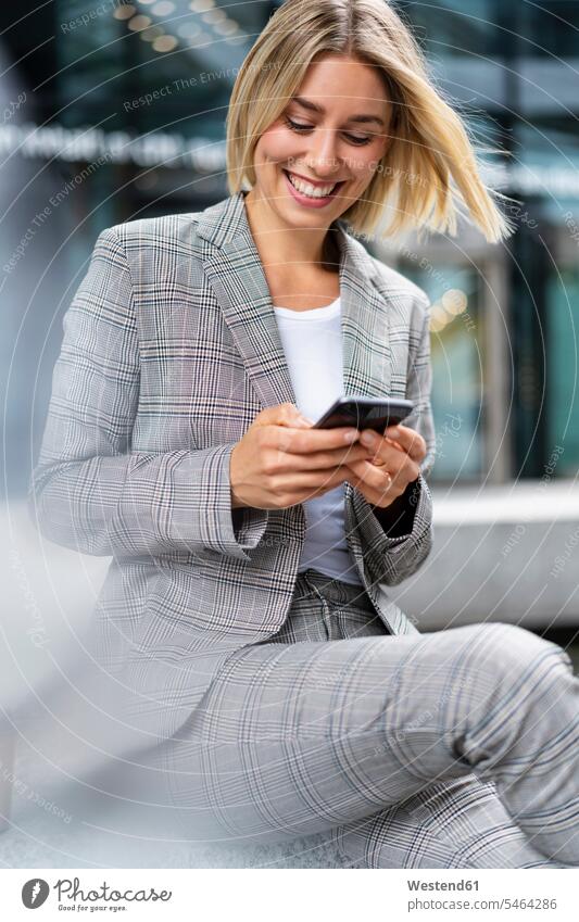 Glückliche junge Geschäftsfrau benutzt Mobiltelefon in der Stadt geschäftlich Geschäftsleben Geschäftswelt Geschäftsperson Geschäftspersonen Businessfrau