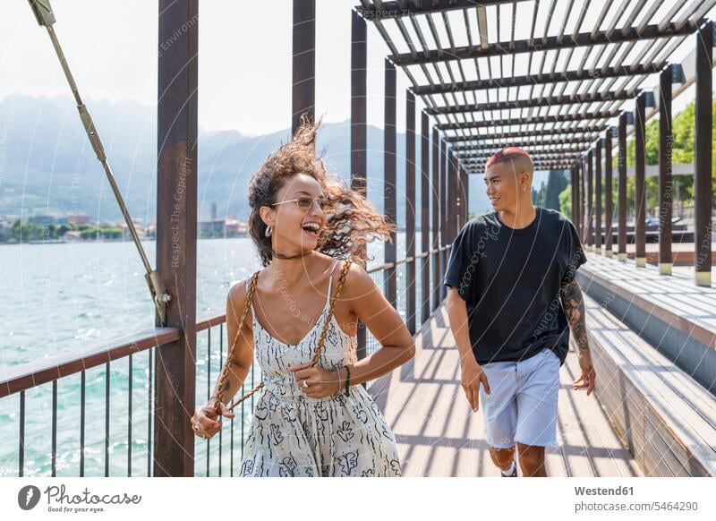 Glückliches junges Paar an der Seepromenade, Lecco, Italien Touristen Rucksäcke freuen Frohsinn Fröhlichkeit Heiterkeit gefühlvoll Emotionen Empfindung