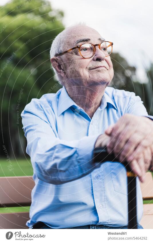 Porträt eines älteren Mannes in einem Park, der sich auf seinen Gehstock stützt Hemden Bänke Sitzbank Sitzbänke Parkbänke Brillen sitzend sitzt entspannen