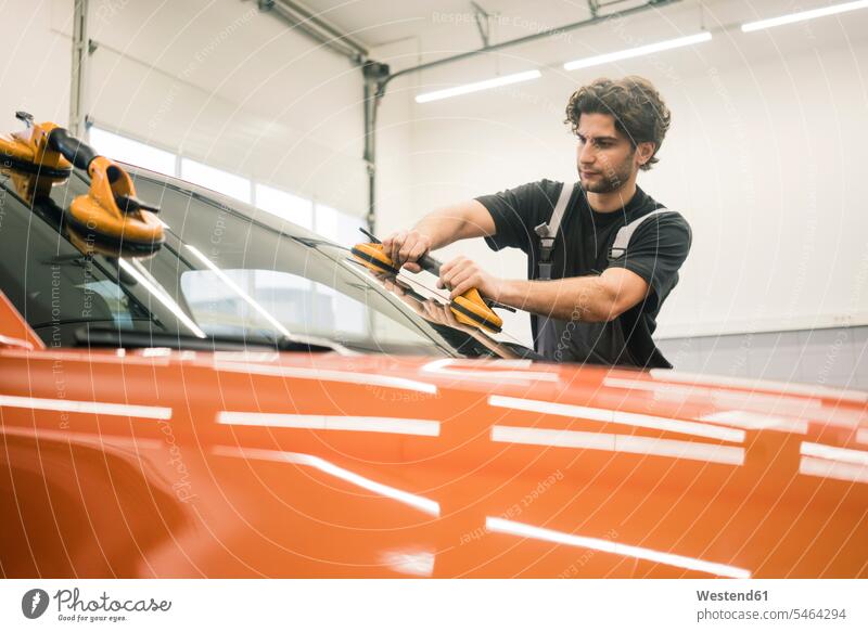 Automechaniker in einer Werkstatt beim Fensterwechsel Job Berufe Berufstätigkeit Beschäftigung Jobs Gewerbe industriell Industrien Monteur Glasscheiben KFZ