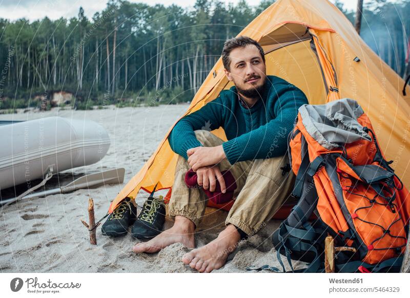 Rucksacktourist sitzt vor seinem Zelt am Strand Beach Straende Strände Beaches Zelte Camp Lager Backpacker sitzen sitzend Tourist Touristen Tourismus unterwegs