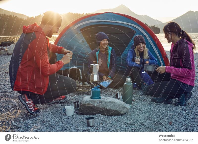 Gruppe von Wanderern zeltet bei Sonnenuntergang am Seeufer Freunde Zelt Zelte Camping Campen zelten Sonnenuntergänge Freundschaft Kameradschaft wandern