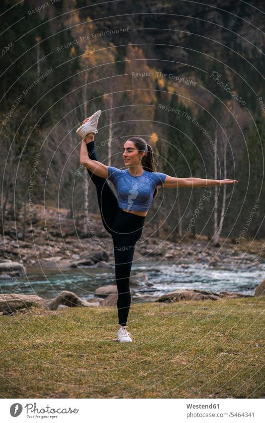 Junge flexible Frau macht Dehnübungen gegen einen Fluss, Ordesa-Nationalpark, Huesca, Spanien Farbaufnahme Farbe Farbfoto Farbphoto Außenaufnahme außen draußen