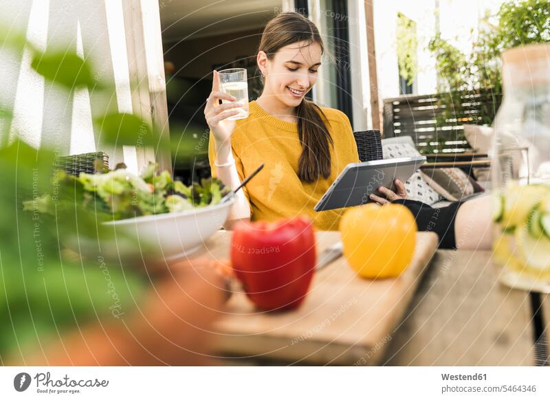 Lächelnde junge Frau mit Gemüse auf dem Tisch, die zu Hause ein Video über ein digitales Tablett anschaut Farbaufnahme Farbe Farbfoto Farbphoto Deutschland