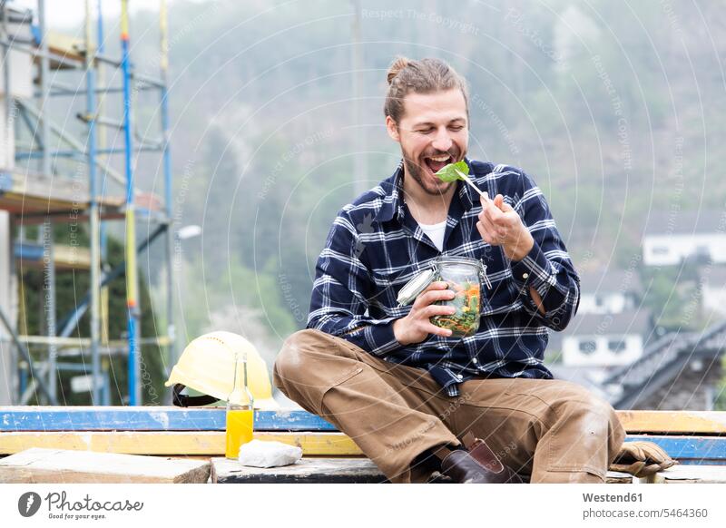 Bauarbeiter isst Salat, während er draußen auf der Baustelle sitzt Farbaufnahme Farbe Farbfoto Farbphoto Deutschland Architektur Baukunst Baustellen