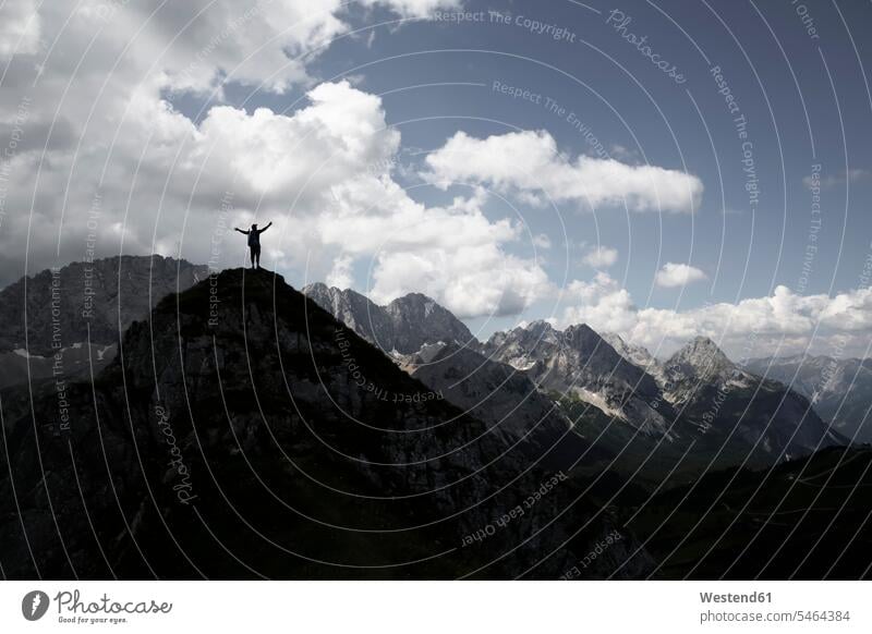 Österreich, Tirol, Silhouette eines jubelnden Mannes auf einem Berggipfel Berge Umriß Gegenlicht Schattenbilder Silhouetten Konturen Umriss Umrisse jauchzen