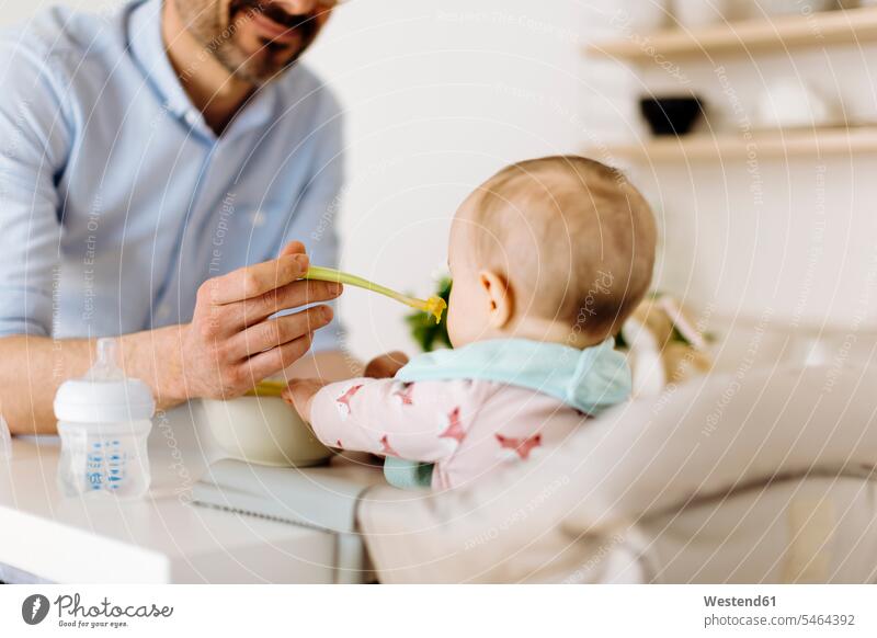 Vater füttert kleines Mädchen im Hochstuhl Schale Schalen Schälchen Schüsseln essend kosten probieren sitzend sitzt zufrieden daheim zu Hause Essen