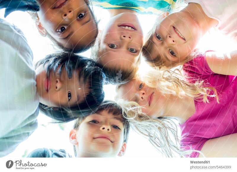 Gruppe von Kindern, die Köpfe zusammenstecken, Blick nach oben Freundschaft lächeln schauen Freude glücklich Zufriedenheit Gemeinsam Außenaufnahme Tag