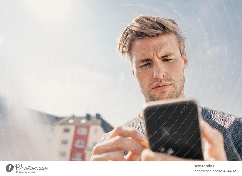 Junger Mann mit Smartphone auf dem Speck Informationen Telekommunikation telefonieren Handies Handys Mobiltelefon Mobiltelefone Lektüre außen draußen im Freien