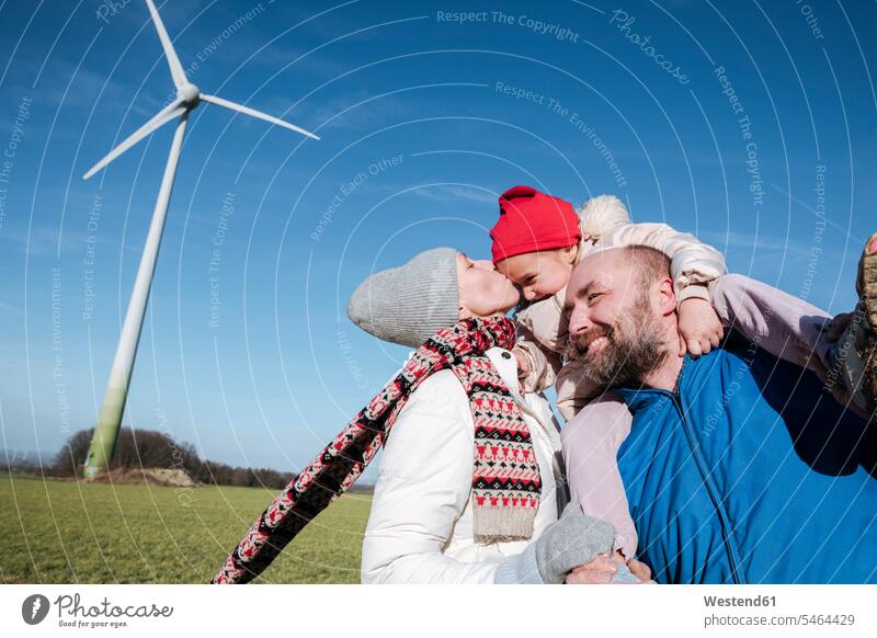 Glückliche Eltern mit kleiner Tochter gegen den Himmel mit Windrad im Hintergrund Umwelt- und Naturschutz Umweltthemen Umweltschutz Ökologie alternative Energie