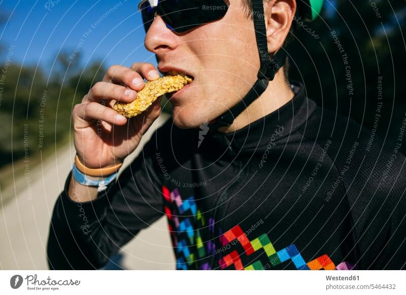 Porträt eines Radfahrers, der an einem sonnigen Tag in einer Pause eine Kleinigkeit isst Raeder Räder Bike Bikes Fahrräder Brillen Sonnenbrillen Muße Dynamik