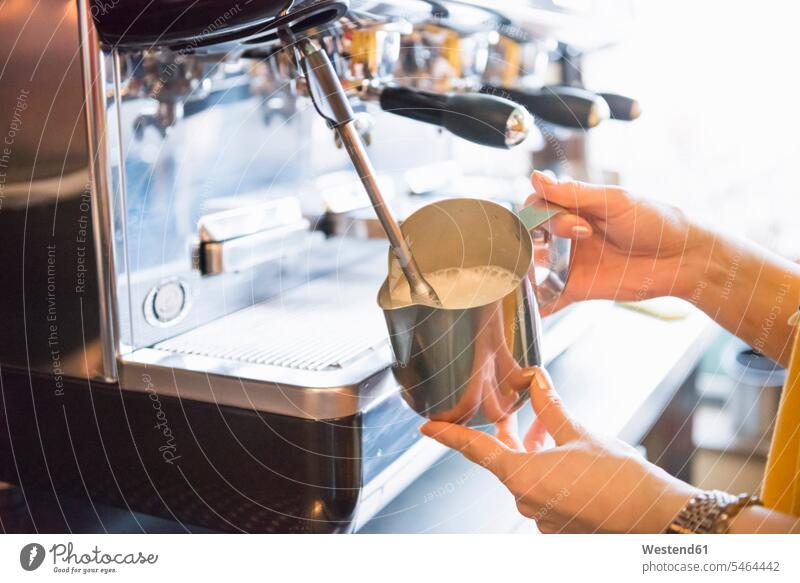 Hände eines weiblichen Barista, der Milch mit der Espressomaschine im Café aufschäumt Farbaufnahme Farbe Farbfoto Farbphoto Innenaufnahme Innenaufnahmen innen