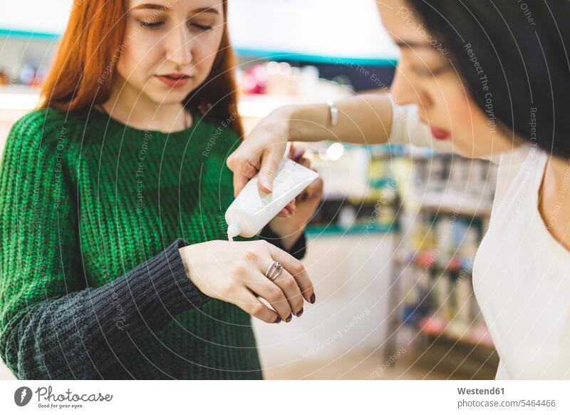 Zwei Frauen in einem Kosmetikgeschäft probieren Handcreme aus Kundin testen Geschäft Shop Laden Läden Geschäfte Shops ausprobieren Kosmetika Schönheitspflege