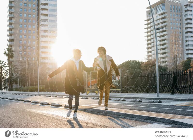 Glückliches Paar läuft in der Stadt bei Sonnenuntergang rennen glücklich glücklich sein glücklichsein Sonnenuntergänge Pärchen Paare Partnerschaft Stimmung