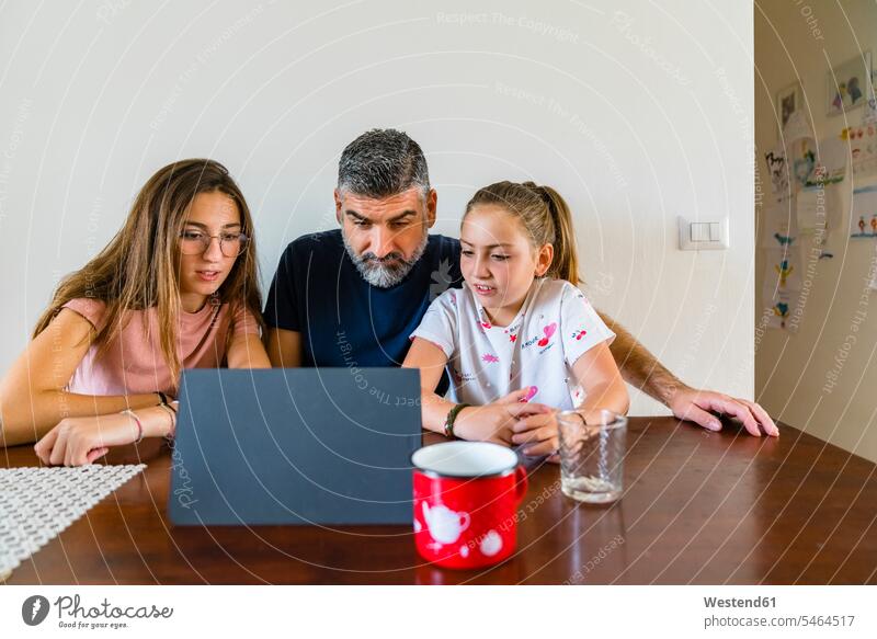 Vater mit zwei Töchtern betrachtet Tafel auf Holztisch zu Hause Gläser Trinkglas Trinkgläser T-Shirts Tische Holztische Medium Videofilm Videos entspannen