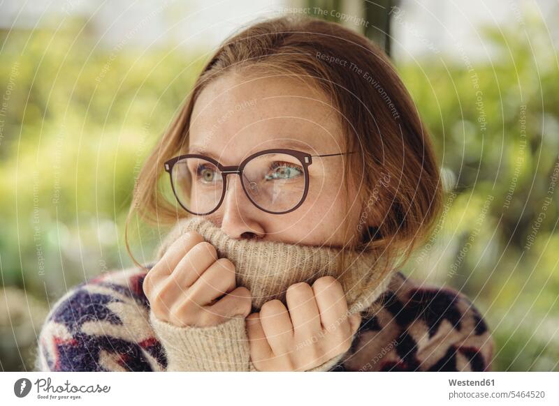 Junge Frau mit Brille, die einen flauschigen Pullover trägt und zur Seite schaut Koepfe Köpfe Gesichter Brillen entspannen relaxen entspanntheit relaxt warm