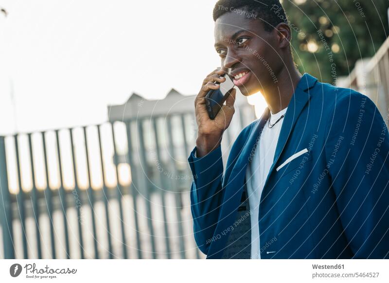 Junger männlicher Profi beim Telefonieren im Freien Farbaufnahme Farbe Farbfoto Farbphoto Außenaufnahme außen draußen Tag Tageslichtaufnahme Tageslichtaufnahmen
