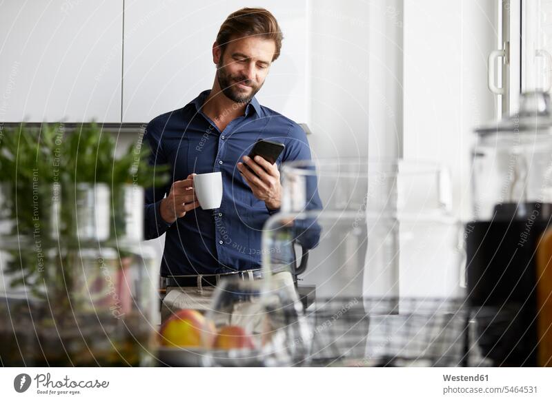 Geschäftsmann benutzt Mobiltelefon beim Kaffeetrinken in der Cafeteria Farbaufnahme Farbe Farbfoto Farbphoto Innenaufnahme Innenaufnahmen innen drinnen Tag
