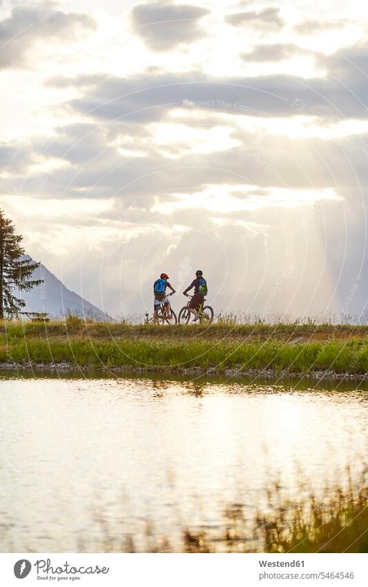 Österreich, Tirol, Mountainbiker im Abendlicht Pause Pause machen Paar Pärchen Paare Partnerschaft Mountainbikerin Mountainbikerinnen Mountainbikefahrerin