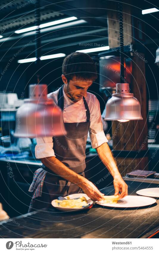 Chefkoch, der in der Küche eines Restaurants Speisen auf Tellern serviert Leute Menschen People Person Personen Europäisch Kaukasier kaukasisch 1 Ein ein Mensch