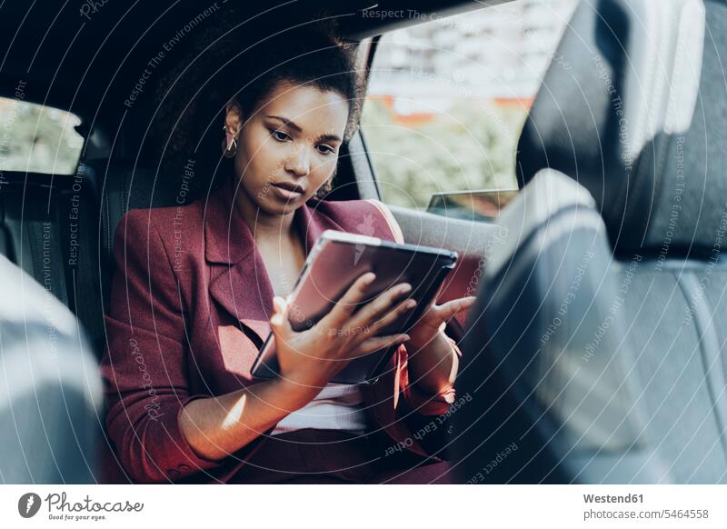 Junge Unternehmerin nutzt digitales Tablet im Auto sitzend Farbaufnahme Farbe Farbfoto Farbphoto Spanien Fahrzeuginnenraum Tag Tageslichtaufnahme