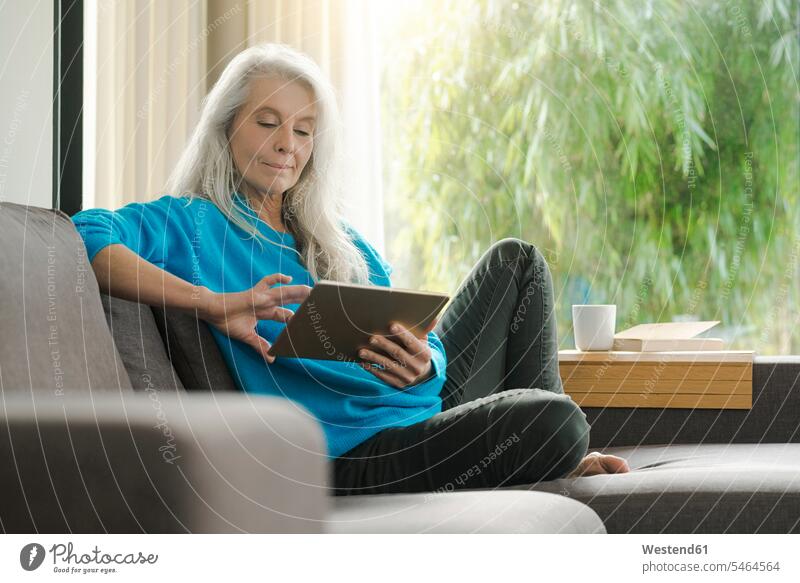 Porträt der reifen Frau sitzt auf der Couch zu Hause mit digitalen Tablette Tablet Computer Tablet-PC Tablet PC iPad Tablet-Computer Zuhause daheim Sofa Couches