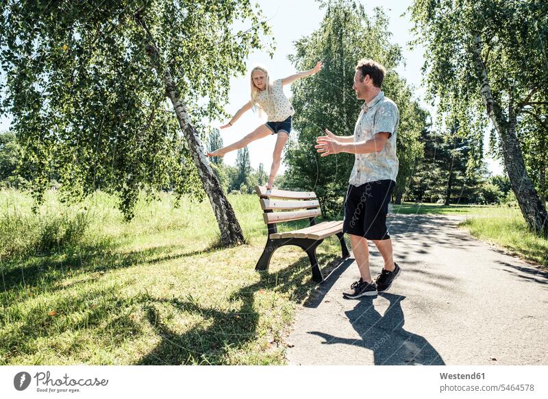 Vater beobachtet Tochter beim Balancieren auf einer Parkbank Leute Menschen People Person Personen Europäisch Kaukasier kaukasisch Nordeuropäisch 2 2 Menschen