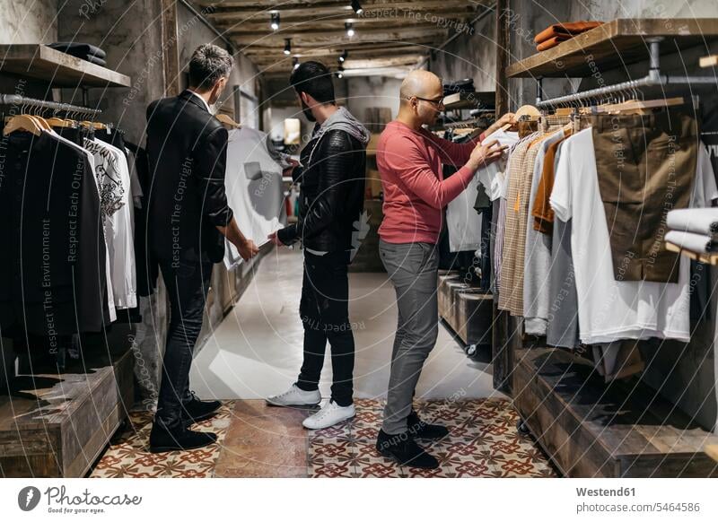 Drei Männer in modernem Herrenbekleidungsgeschäft mit neuer Kollektion Kunde Kunden Kundschaft Herrenmode zeigen vorführen präsentieren Vorführung herzeigen