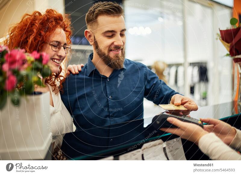Glückliches Paar beim Bezahlen am Tresen im Blumenladen Kunde Kunden Kundschaft glücklich glücklich sein glücklichsein Blumengeschäft Blumengeschaeft