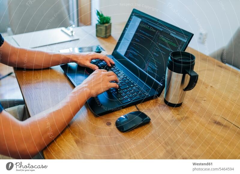 Männlicher Webdesigner programmiert am Laptop am Schreibtisch im Büro durch Farbaufnahme Farbe Farbfoto Farbphoto Innenaufnahme Innenaufnahmen innen drinnen Tag