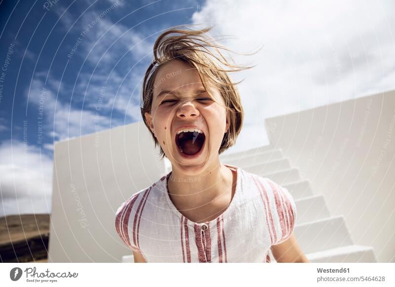 Mädchen mit zerzaustem Haar, laut schreiend rufen rufend Schrei Trotz Baukunst Bauwerke Gebäude Treppen Treppenaufgang Wolken außen draußen im Freien am Tag