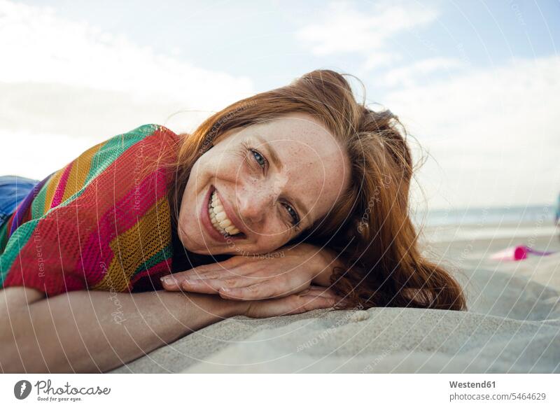 Rothaarige Frau liegt mit geschlossenen Augen im Sand am Strand Beach Straende Strände Beaches sandig lächeln rothaarig rote Haare rothaarige rotes Haar