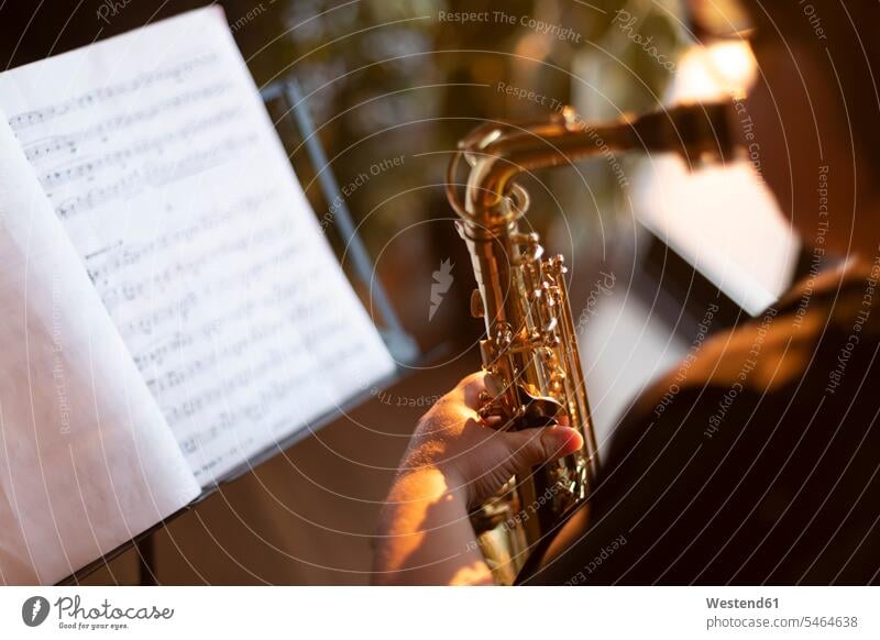 Schnittansicht eines Jungen, der zu Hause Saxophon spielt ausüben trainieren Übung abends daheim Muße Kreativ sonnig stimmungsvoll Sonnenuntergänge drinnen