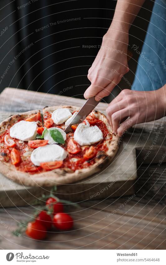 Junger Mann bereitet Pizza vor, schneidet Pizza schneiden Hand Hände Zubereitung zubereiten Pizzen Pizzastück Pizzastücke Männer männlich Messer Mensch Menschen