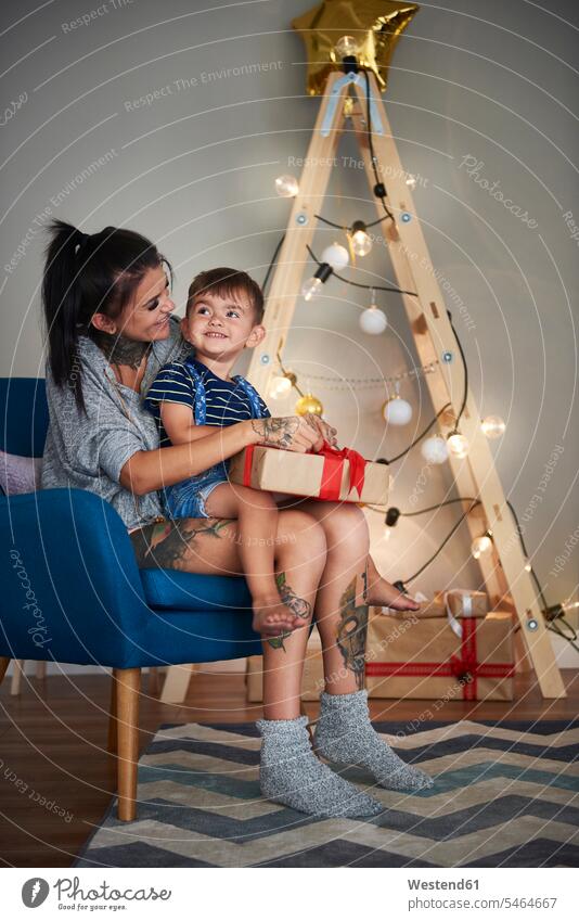 Glücklicher Junge öffnet Weihnachtsgeschenk mit seiner Mutter zu Hause glücklich glücklich sein glücklichsein Familie Familien Weihnachten Christmas X-Mas X mas