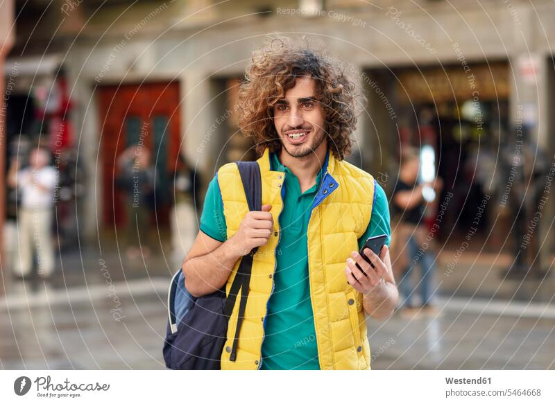 Spanien, Granada, Porträt eines lächelnden jungen Touristen mit Rucksack beim Entdecken der Stadt Mann Männer männlich Rucksäcke entdecken staedtisch städtisch