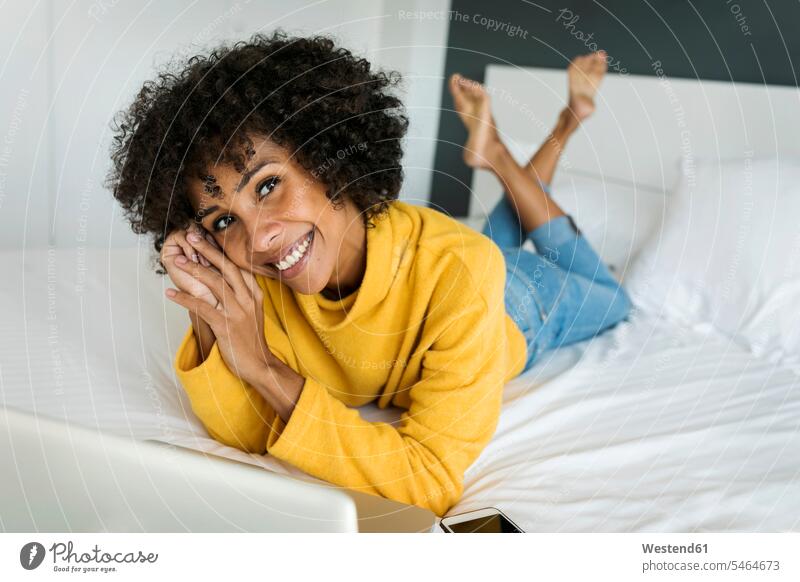 Porträt der glücklichen Frau auf dem Bett liegend mit Laptop liegt Glück glücklich sein glücklichsein Notebook Laptops Notebooks weiblich Frauen Portrait