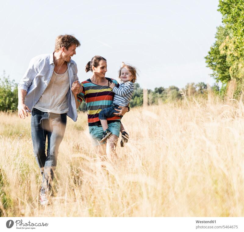 Glückliche Familie beim Spaziergang am Flussufer an einem schönen Sommertag gehen gehend geht glücklich glücklich sein glücklichsein Wiese Wiesen Sommerzeit