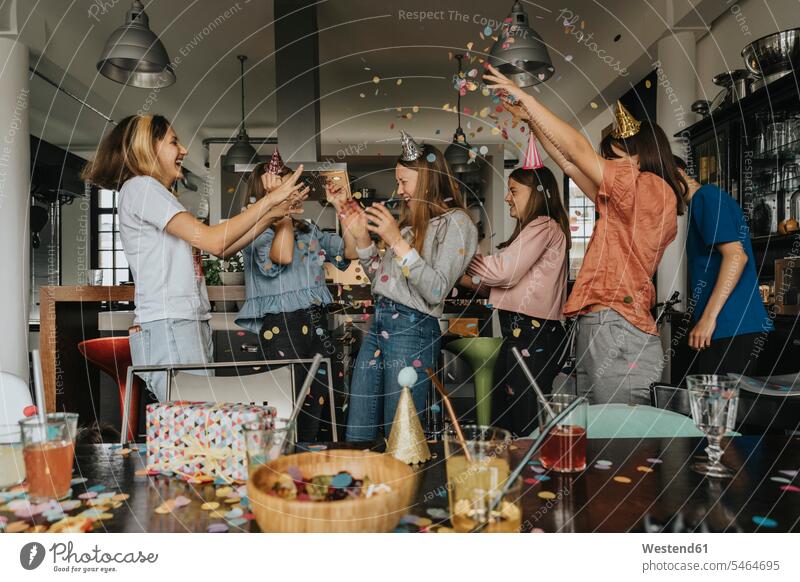 Fröhliche Freunde werfen beim Feiern zu Hause Konfetti auf das Geburtstagskind Farbaufnahme Farbe Farbfoto Farbphoto Deutschland Innenaufnahme Innenaufnahmen