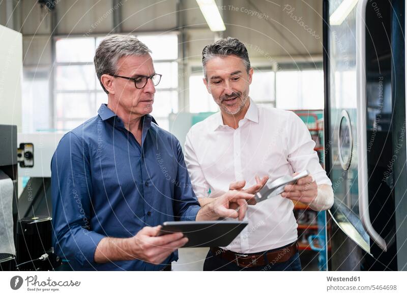 Geschäftsleute in einer Fabrik, die eine Besprechung haben und ein digitales Tablet benutzen Arbeitskollege Arbeitskollegen Kollege Job Berufe Berufstätigkeit